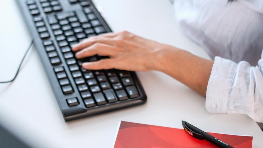 Eine Hand, die auf einer Tastatur tippt