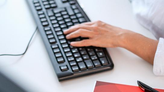Eine Hand, die auf einer Tastatur tippt